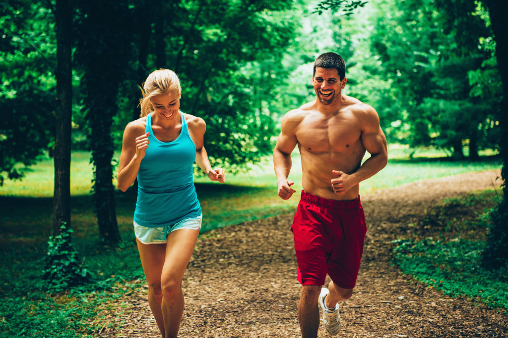 Cheerful young couple jogging in forest